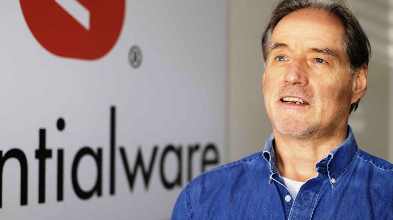 Man in blue shirt in front of Essentialware logo
